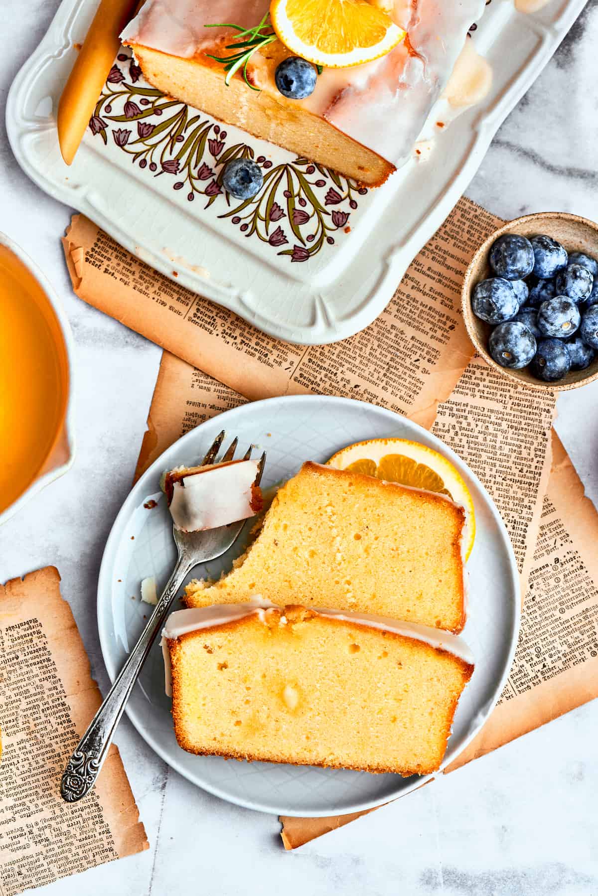 Slices of orange cake are arranged on a blue plate while a fork cuts into one of the pieces.