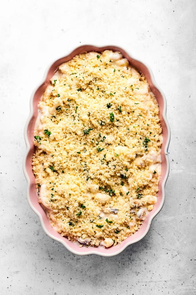 Seafood mac and cheese topped with parmesan breadcrumbs ready to go in the oven.