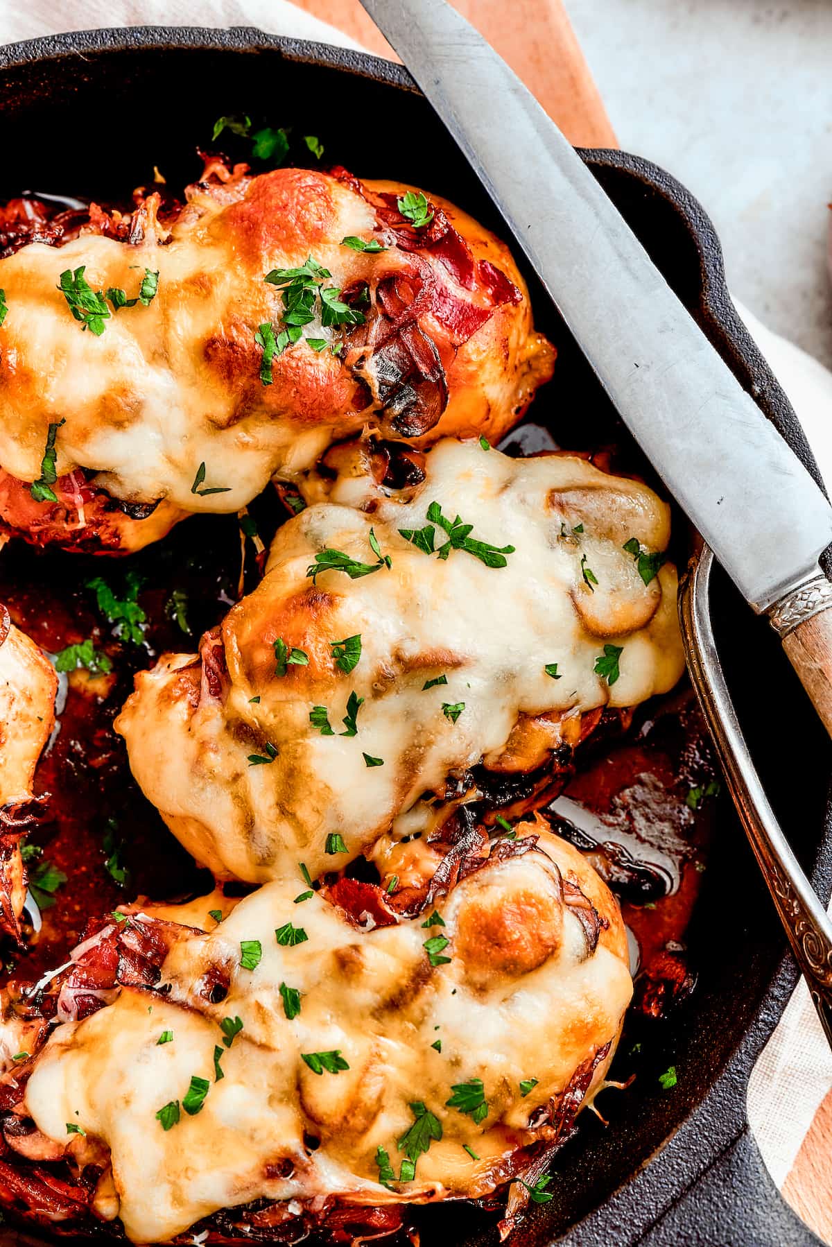 A skillet shows three chicken breasts topped with melted cheese for Alice Springs chicken.