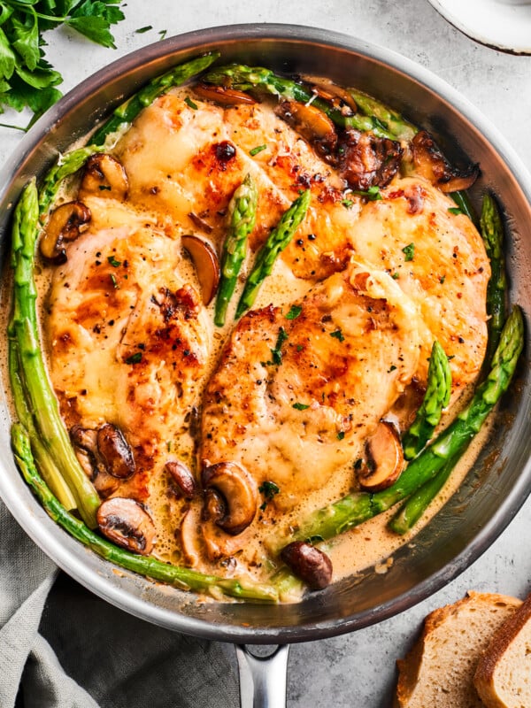 Overhead image of Chicken Madeira in a skillet with asparagus spears and mushrooms.