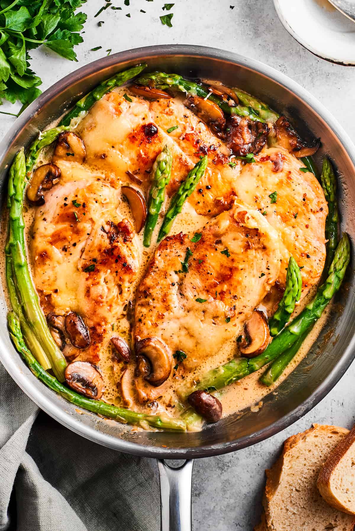 Overhead image of Chicken Madeira in a skillet with asparagus spears and mushrooms.