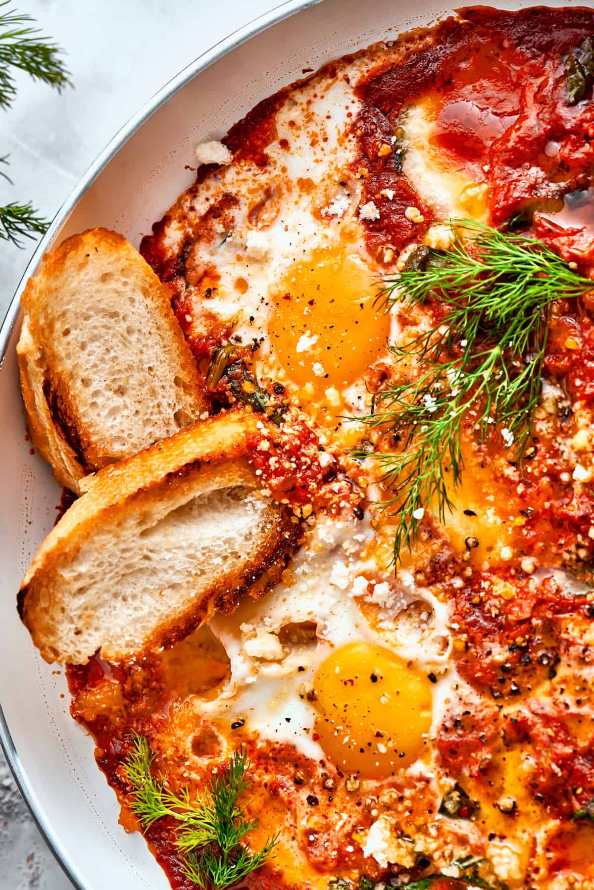 Up close image of two slices of bread resting in the sauce of eggs in purgatory.
