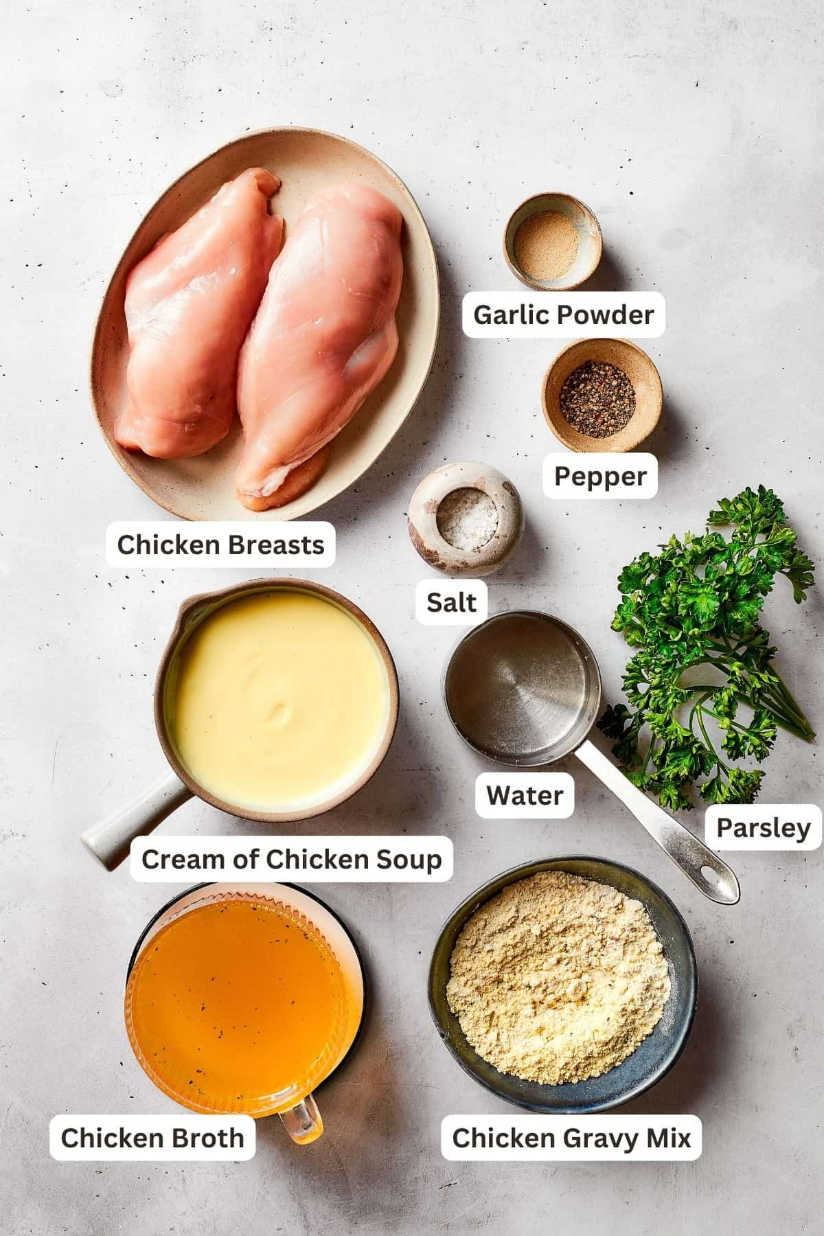The ingredients for chicken and gravy are shown portioned out: chicken breasts, parsley, cream of chicken soup, pepper, salt, garlic powder, water, chicken broth, chicken gravy mix.
