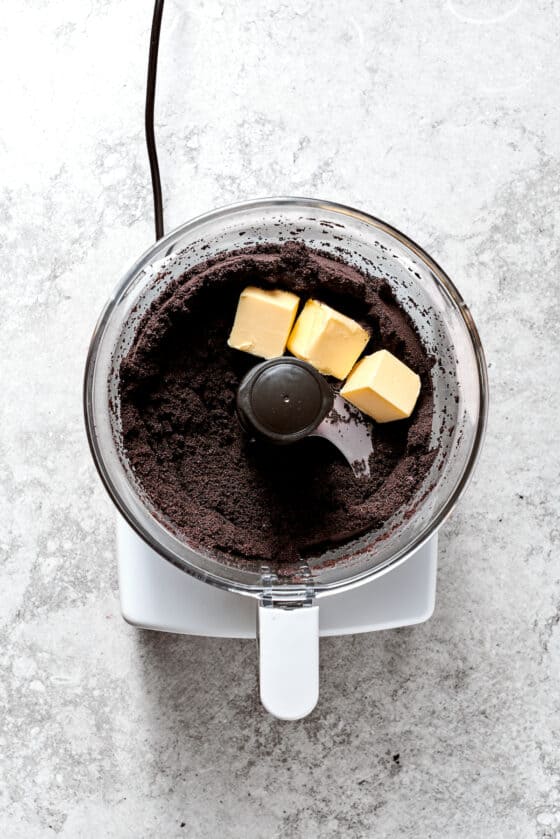 Oreos and cubes of butter in a food processor.