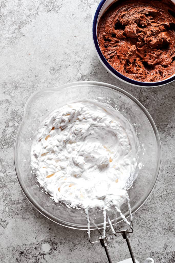 A bowl of whipped cream next to a bowl of chocolate filling.