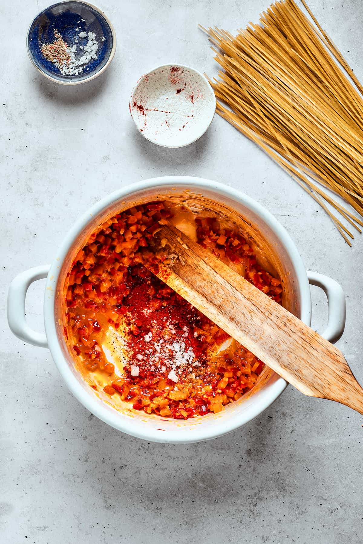 Sautéing Vegetables for Spicy Chicken Soup Base A wooden spoon gently stirs a colorful medley of sautéing vegetables, including finely chopped carrots, shallots, and garlic, in a large, heavy-bottomed soup pot, creating the aromatic base for the spicy chicken soup.