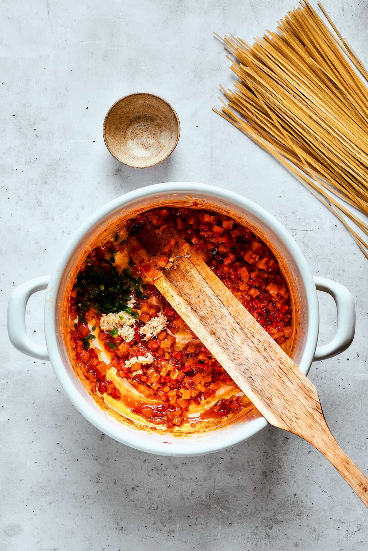 Mixing Ingredients in a Pot of Spicy Chicken Soup A wooden spoon expertly mixes various ingredients, including vibrant spices and liquids, into a simmering pot of spicy chicken soup, ensuring all the flavors are thoroughly combined.