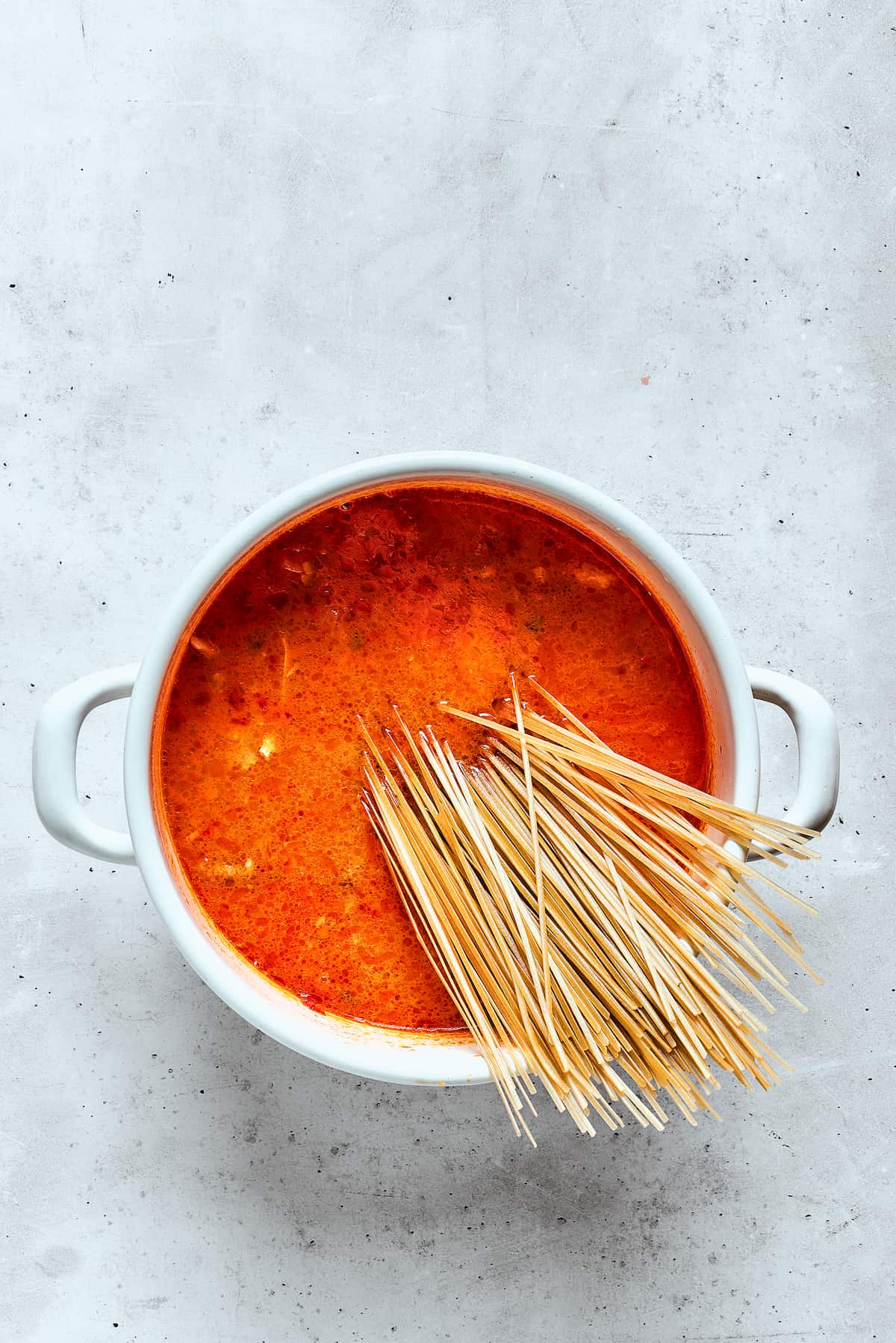 Incorporating Rice Noodles into the Soup A handful of thin rice noodles is gently dropped into a bubbling pot of flavorful spicy chicken soup, where they will quickly soften and absorb the rich broth.