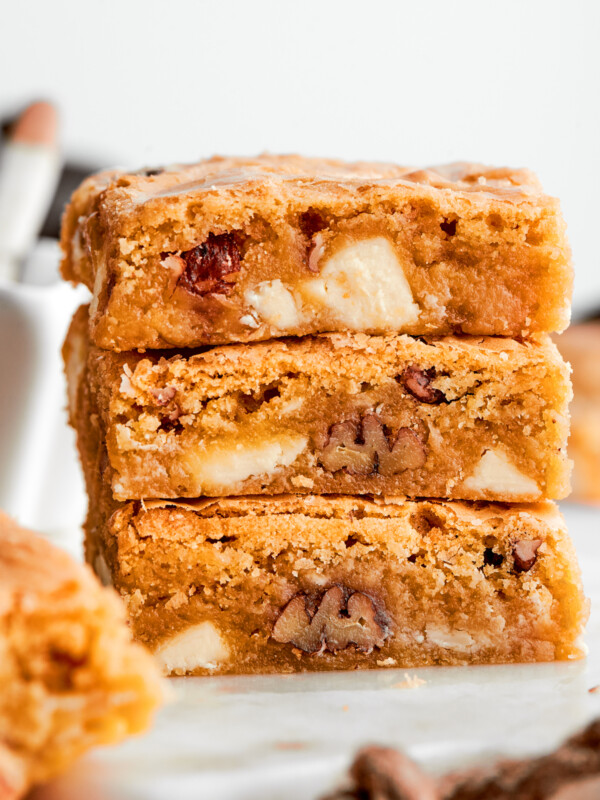 A stack of three blonde brownies with white chocolate chips and pecans visible.