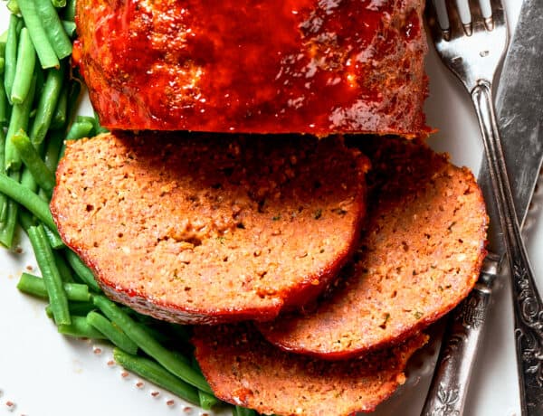 Overhead close-up photo of sliced brown sugar meatloaf served with green beans.