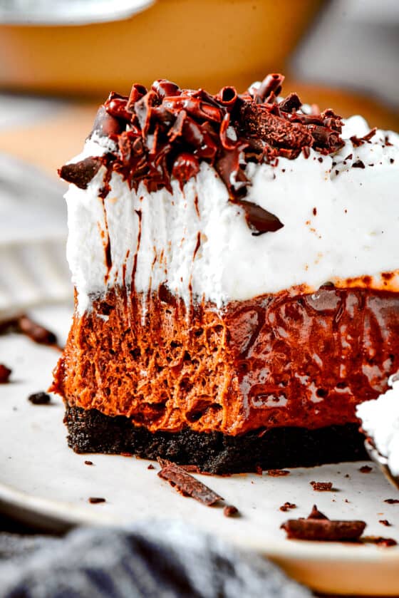 A piece of French silk pie on a plate with a fork on the side holding a bite of pie.