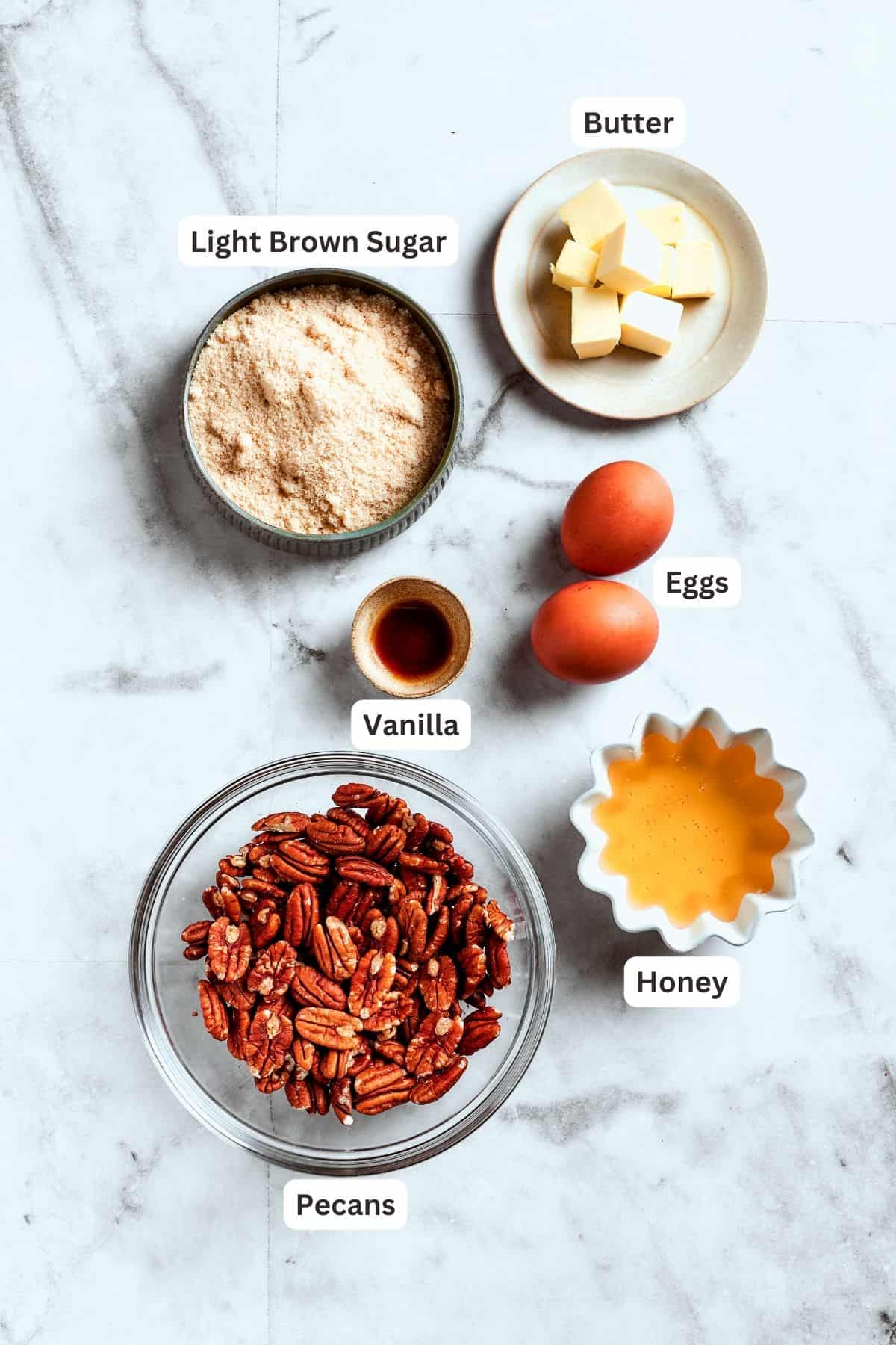 The filling ingredients for pecan pie brownies are shown: pecans, vanilla, eggs, honey, brown sugar.