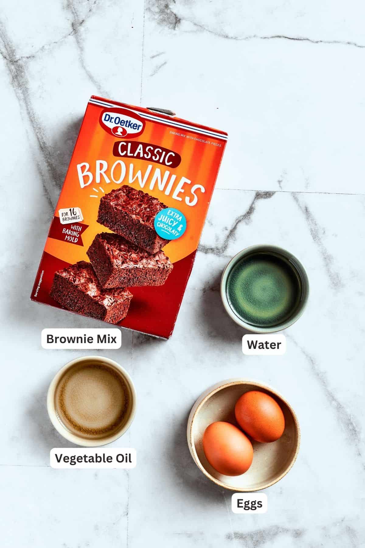 The ingredients for pecan pie brownies are shown: brownie mix, eggs, water, oil.