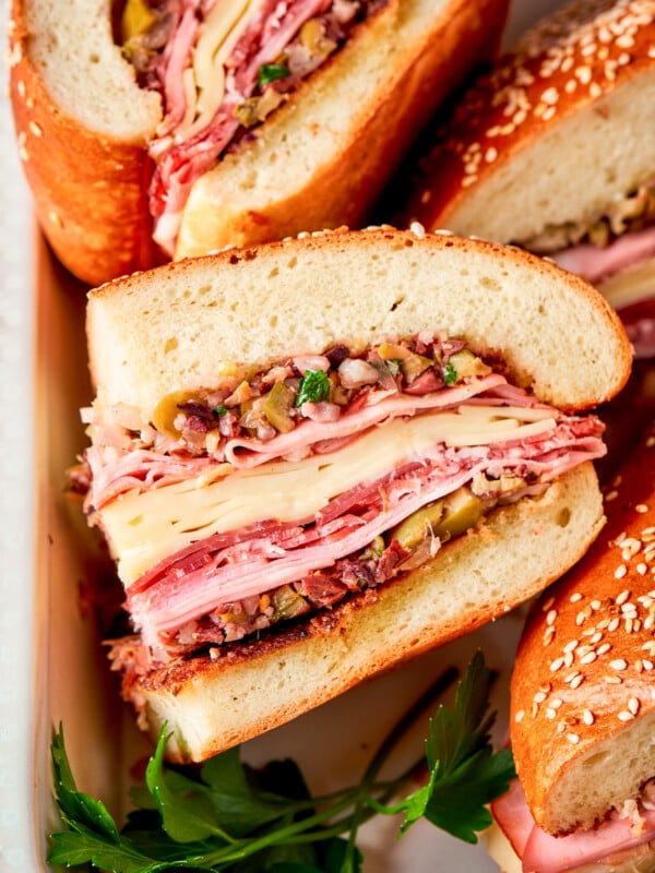 Muffaletta sandwich are shown on their sides with meat and cheese visible.