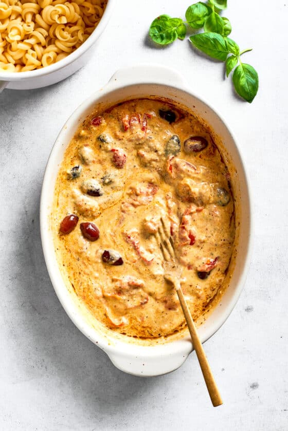 The melted cheese sauce with olives and tomatoes is shown in the baking dish.