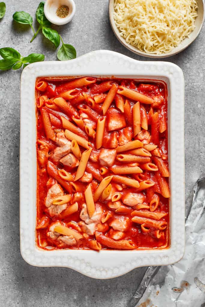 The sauce, pasta, and chicken are added to the baking dish.