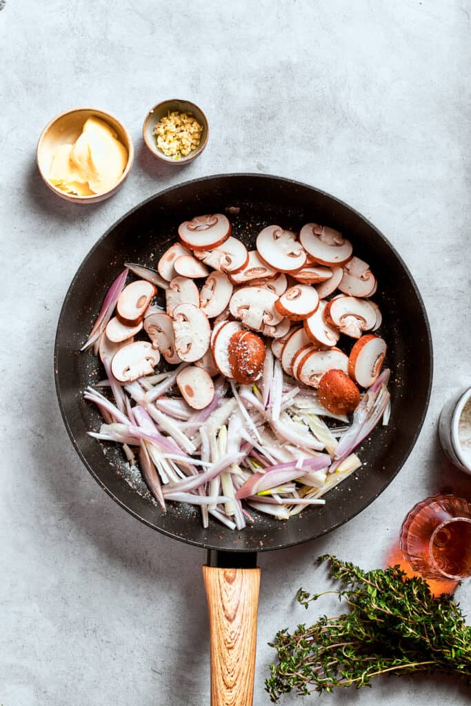Mushrooms, shallots, and garlic cook in a pan.