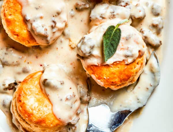 Sausage and gravy biscuits served on an oval white serving dish.