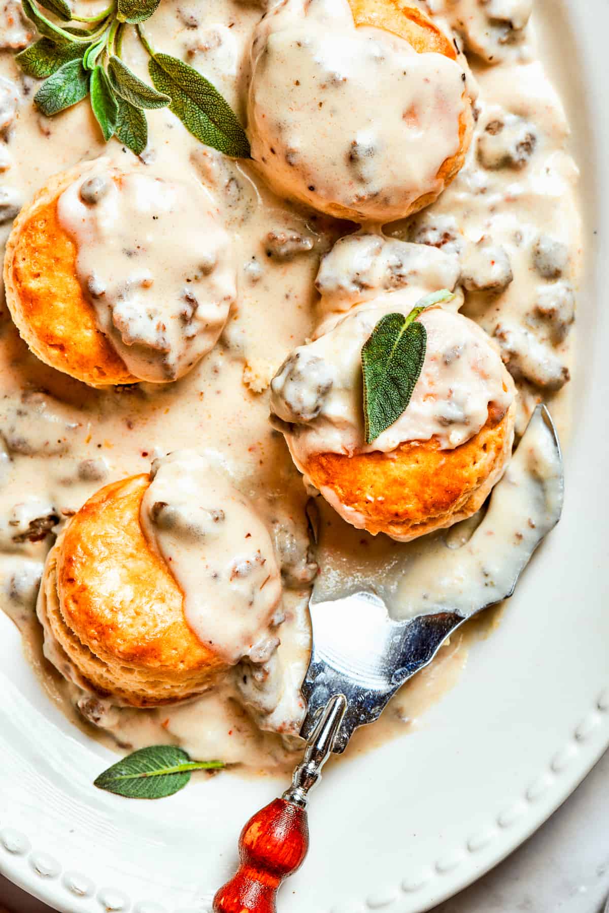 Sausage and gravy biscuits served on an oval white serving dish.