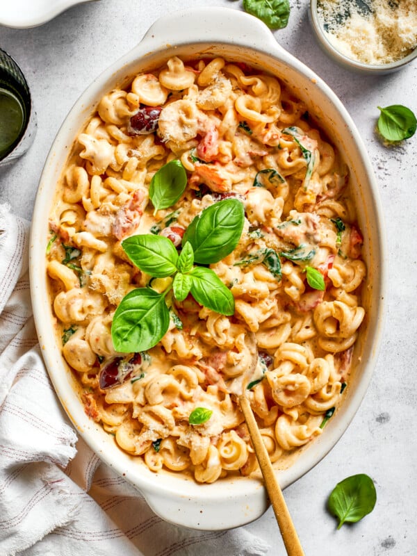 Baked pasta in a casserole dish garnished with fresh basil leaves.