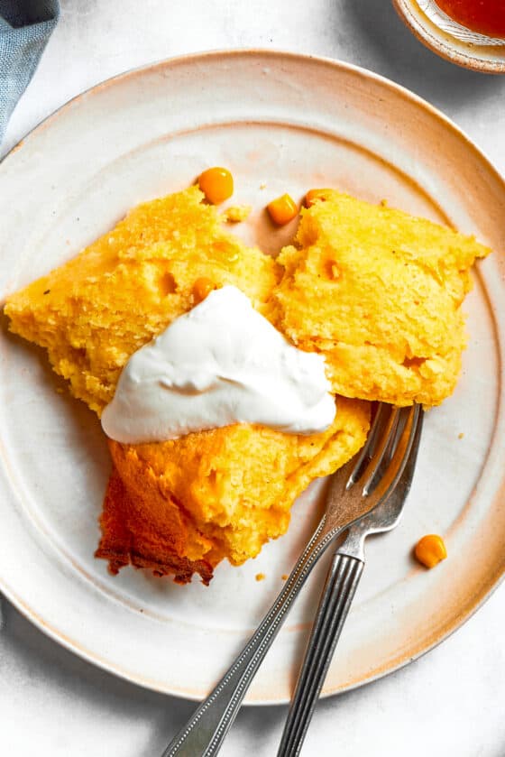 Spoon Bread served on a plate and topped with sour cream.