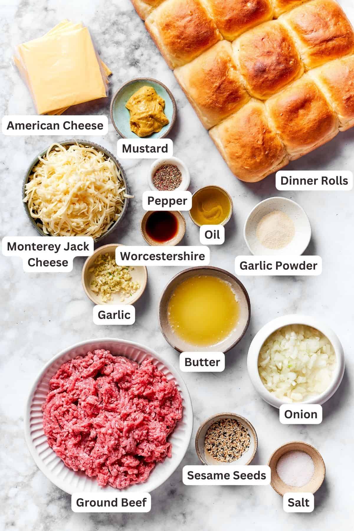 The ingredients for cheeseburger sliders are shown portioned out and labeled: rolls, beef, American cheese, Jack cheese, Worcestershire sauce, garlic powder, oil, butter, onion, garlic, garlic powder, mustard, salt and pepper.