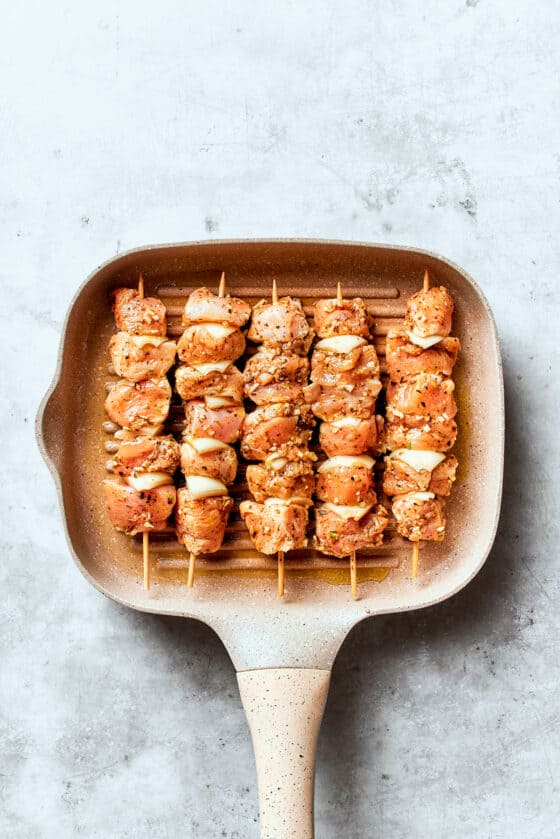 The souvlaki chicken skewers are shown in a grill pan.