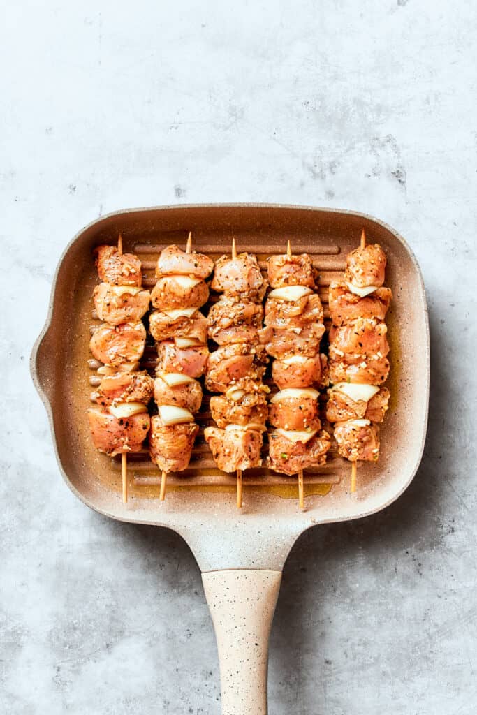 The souvlaki chicken skewers are shown in a grill pan.