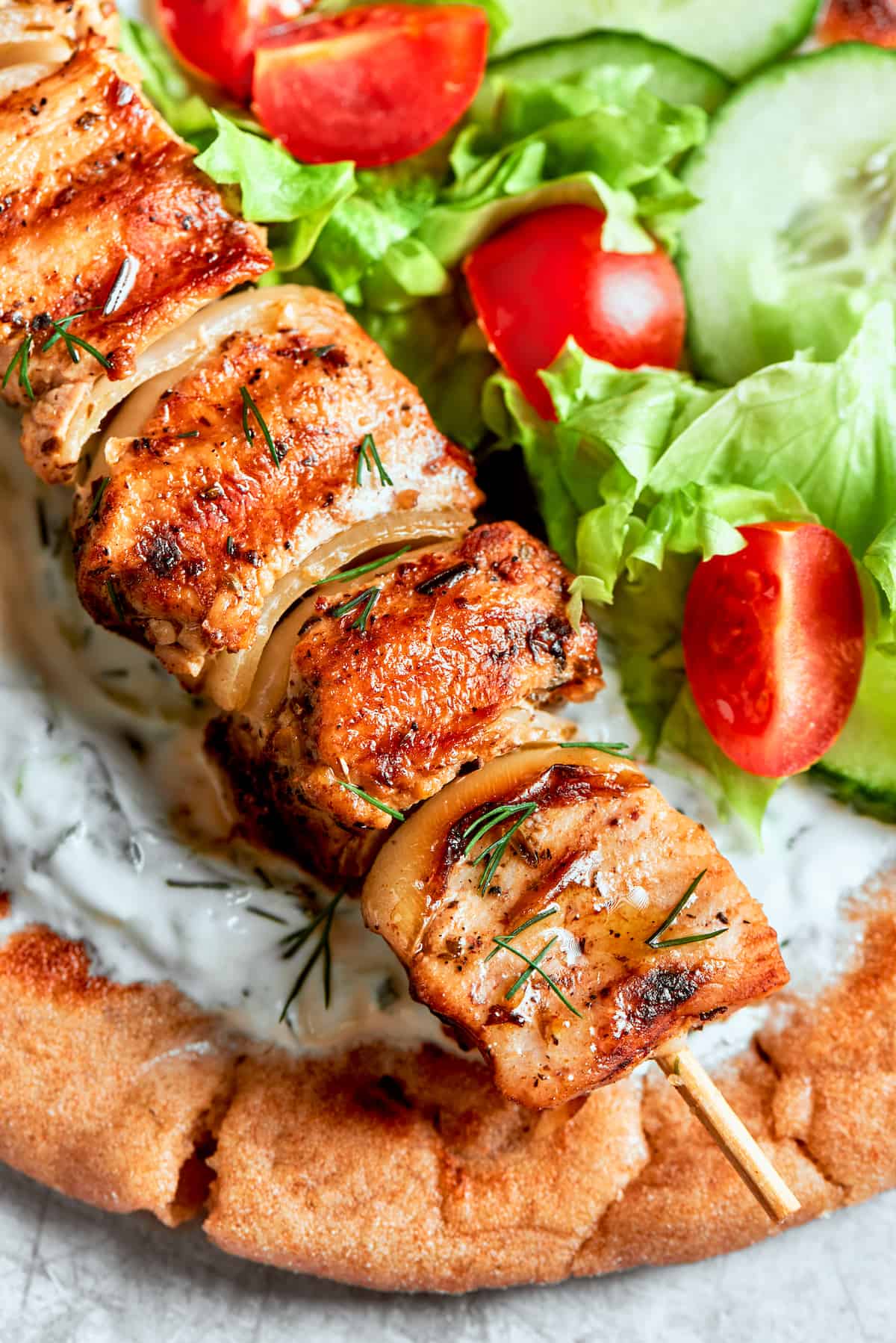 A close up of chicken souvlaki on top of bread.
