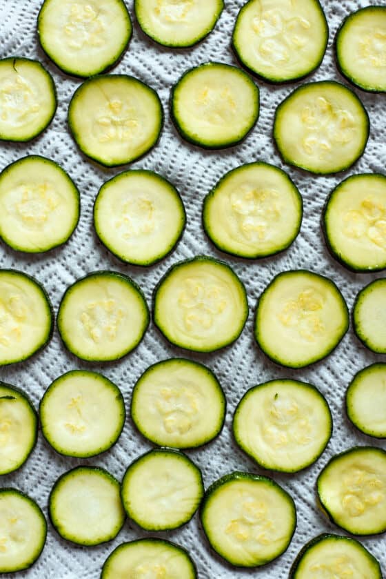 Zucchini slices are arranged on a baking sheet.