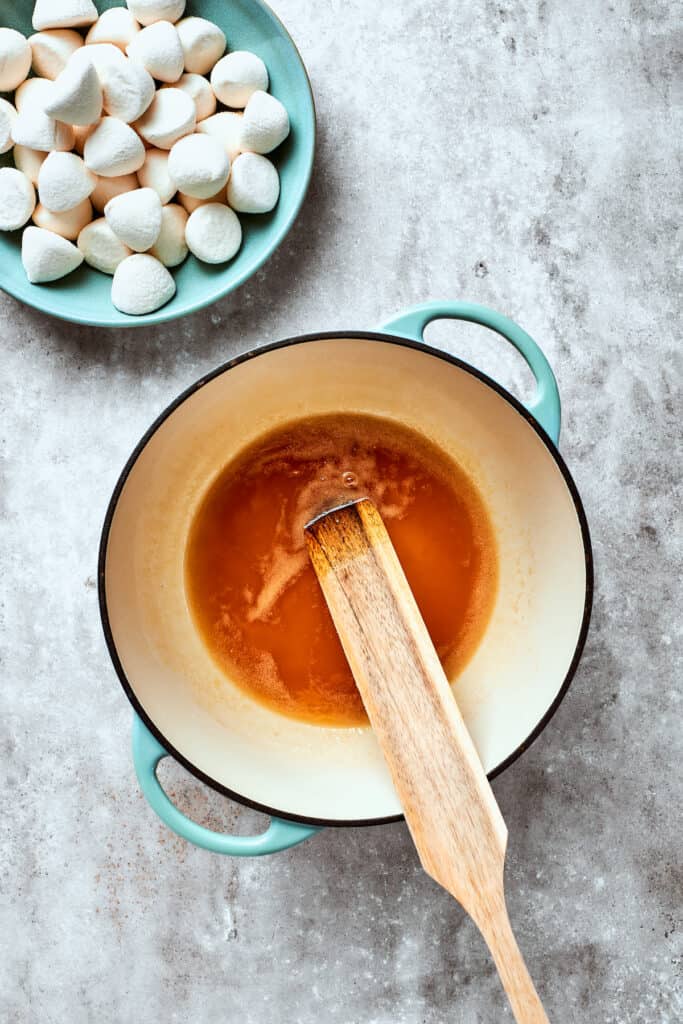 A spoon stirs the butter and maple syrup.