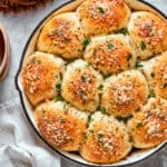 A skillet of baked pizza bites next to a bowl of sauce.