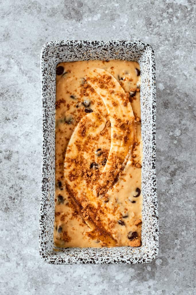 The bread batter is placed in a loaf pan and topped with bananas.