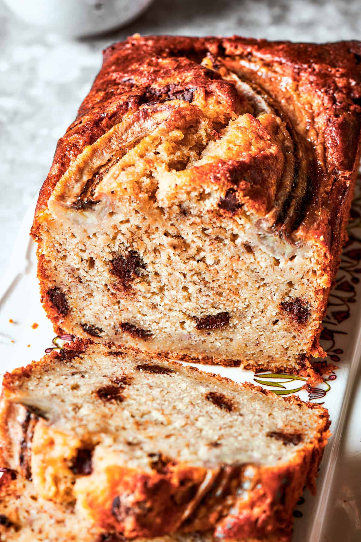 Close-up image of a cut sour cream banana bread with the interior exposed to see the texture and chocolate chips.