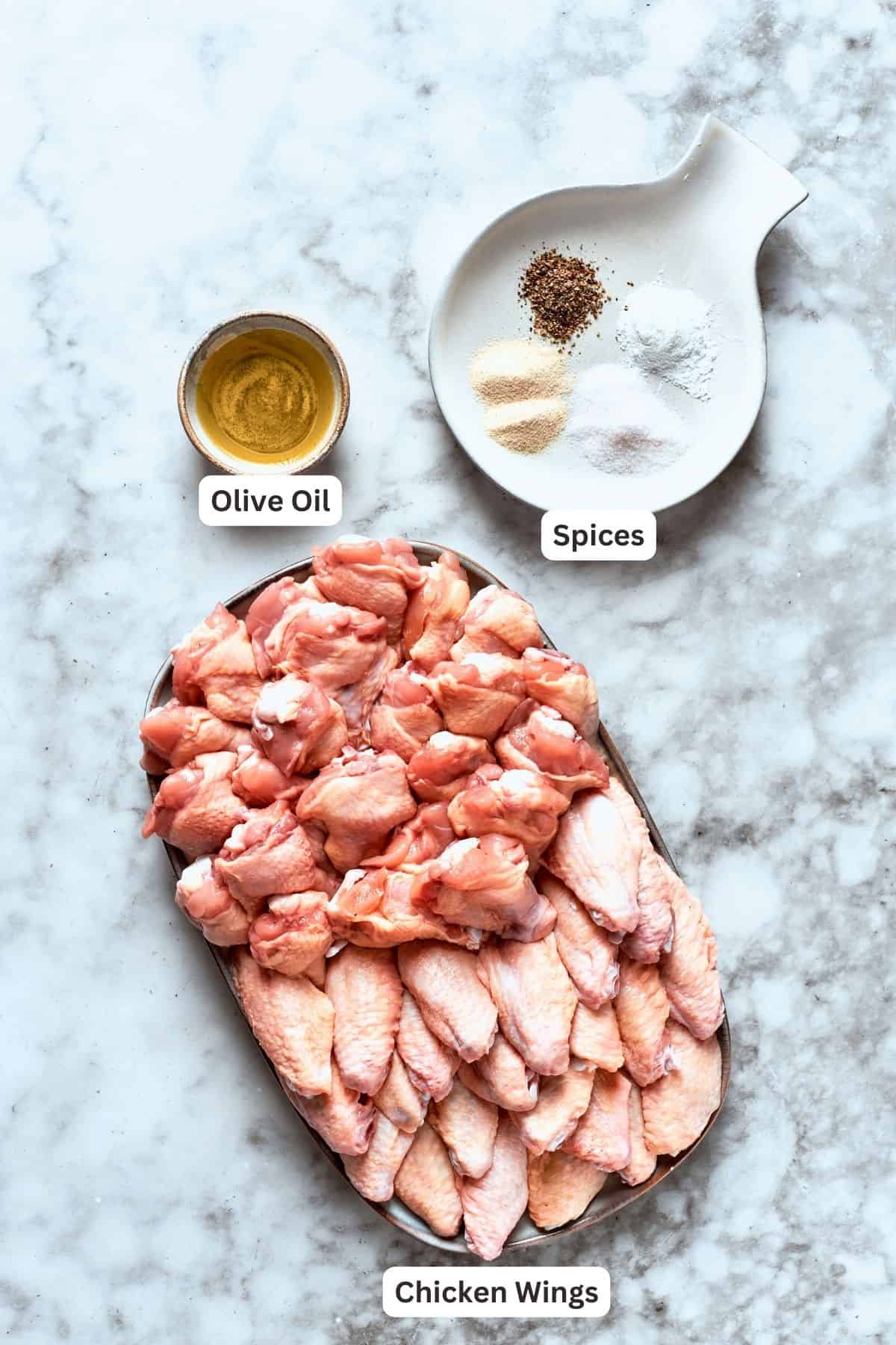Ingredients for buffalo wings are labeled and portioned: chicken, olive oil, spices, baking powder.