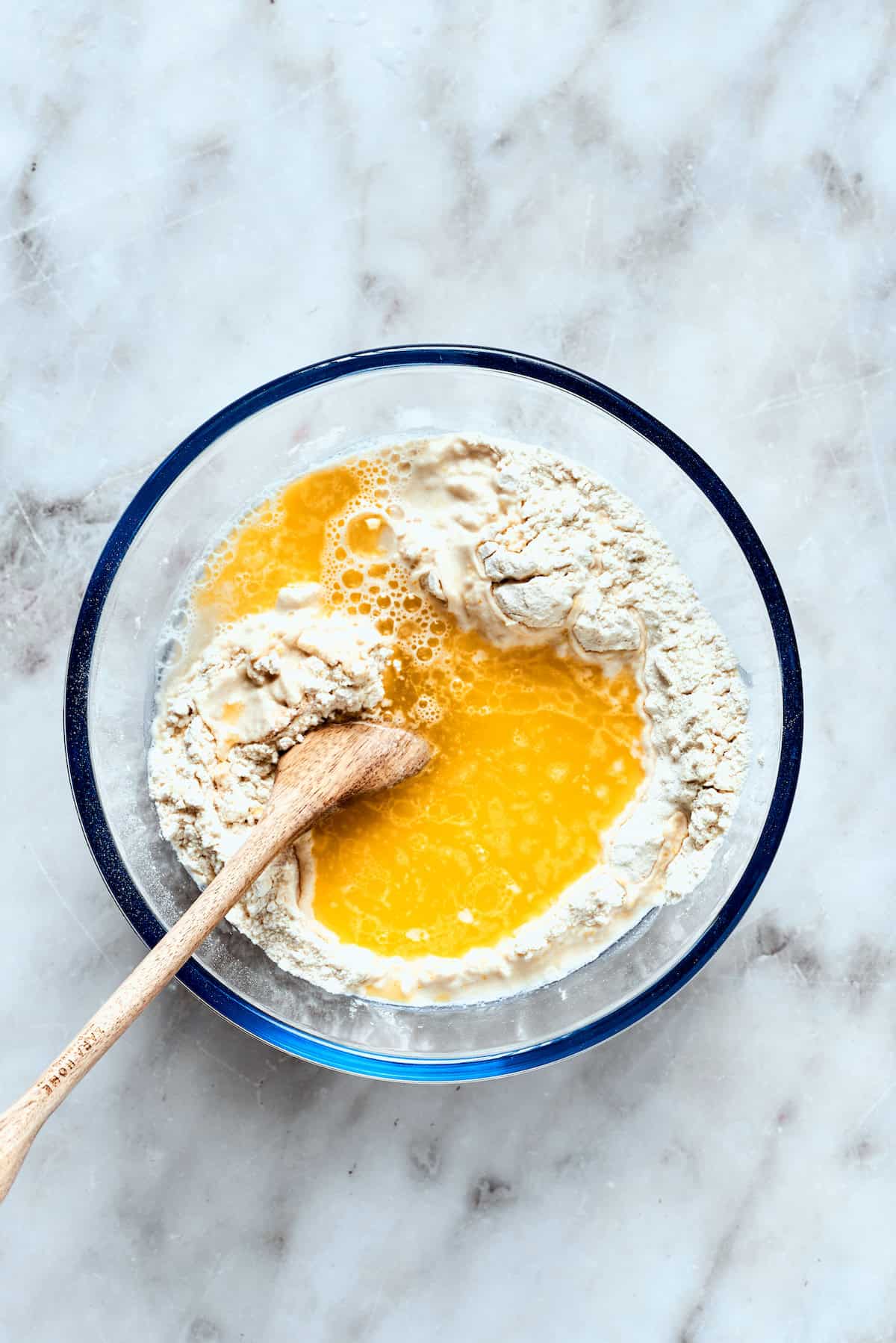 Warm water and melted butter are being stirred into the dry dough ingredients.