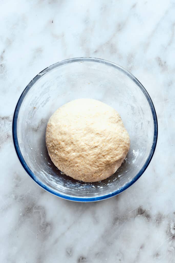 A glass bowl holds the pizza dough ball.