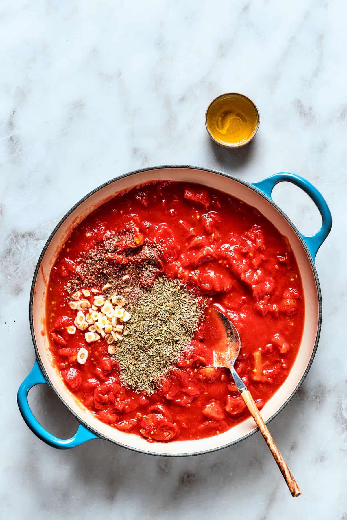 A thick, simmering tomato sauce with visible spices cooking in a saucepan.