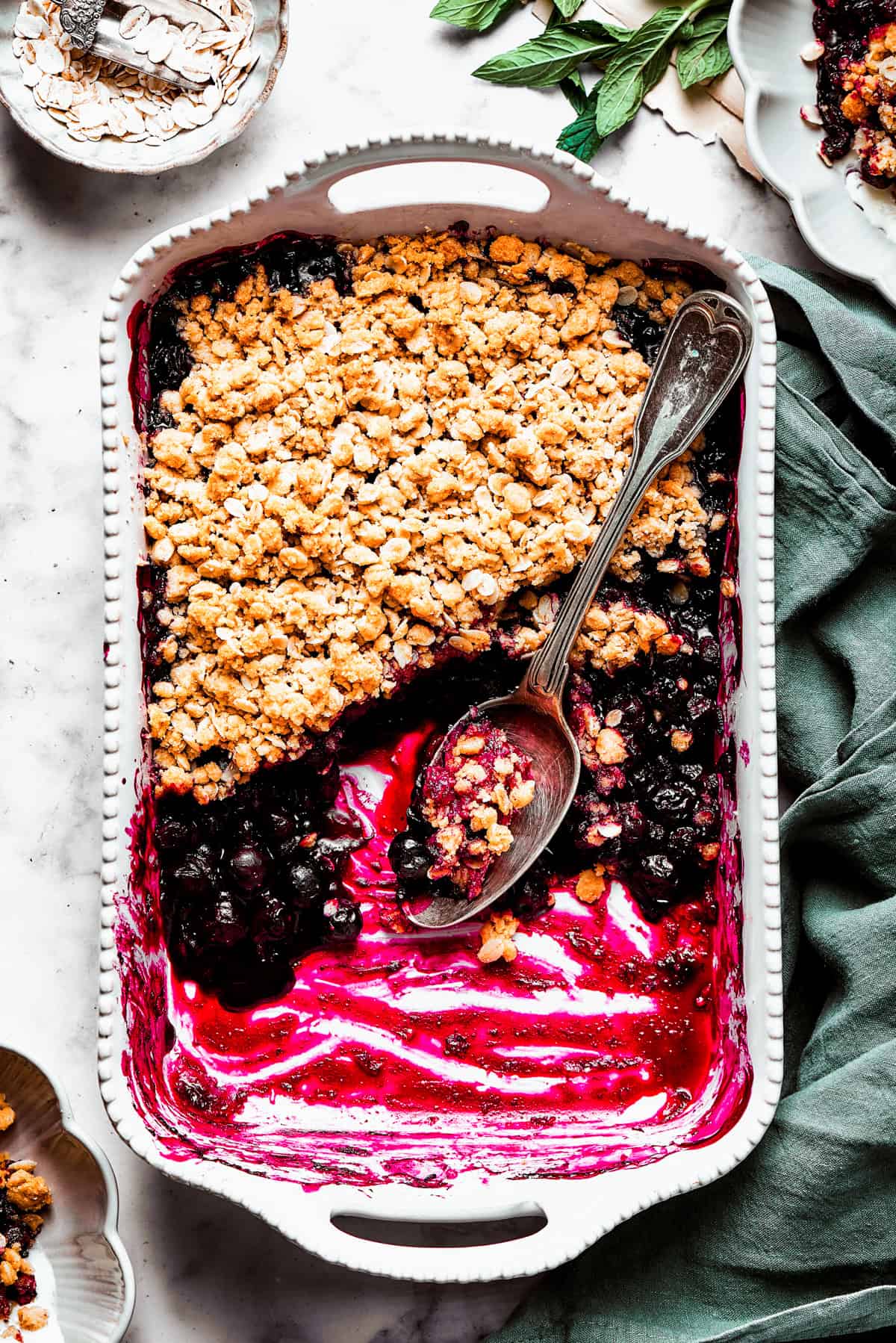 Overhead image of a blueberry crisp in a baking dish, with half of the crisp scooped out.