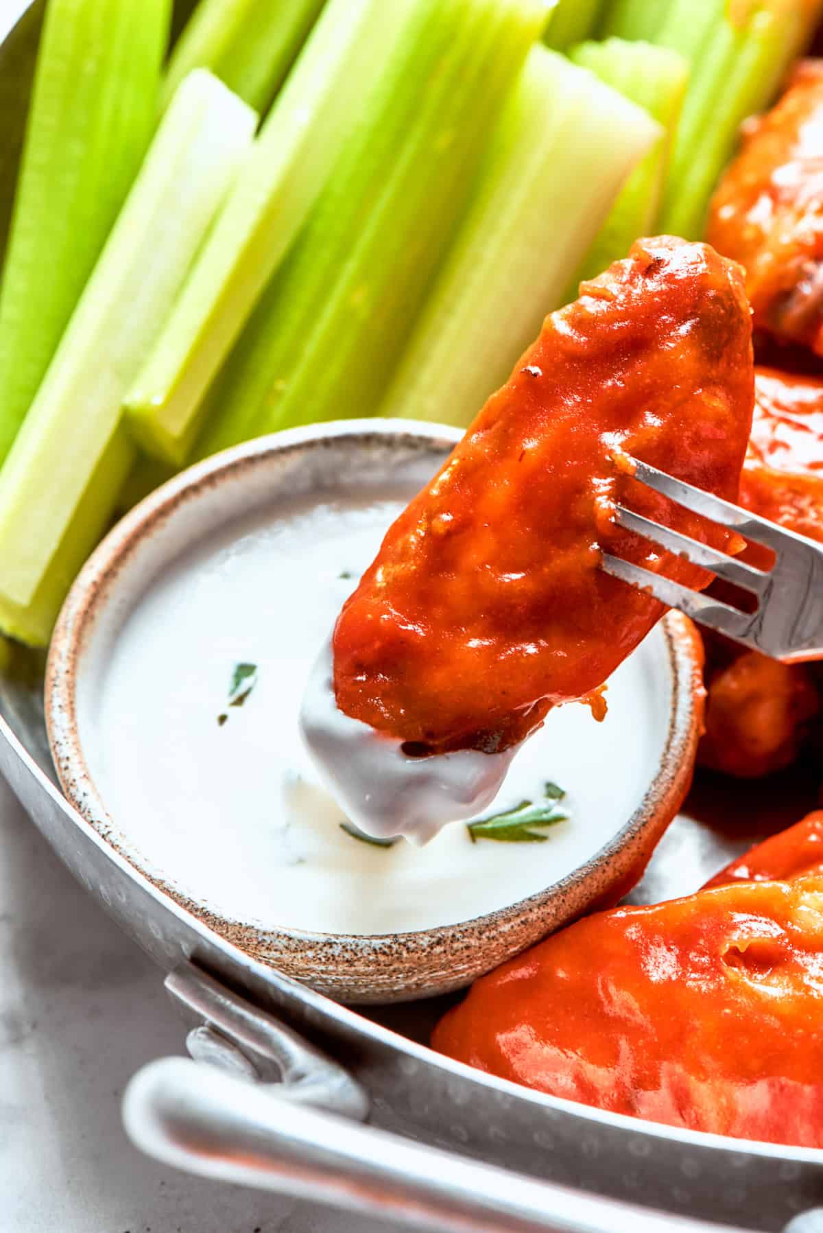 Dipping a chicken wing into ranch sauce.