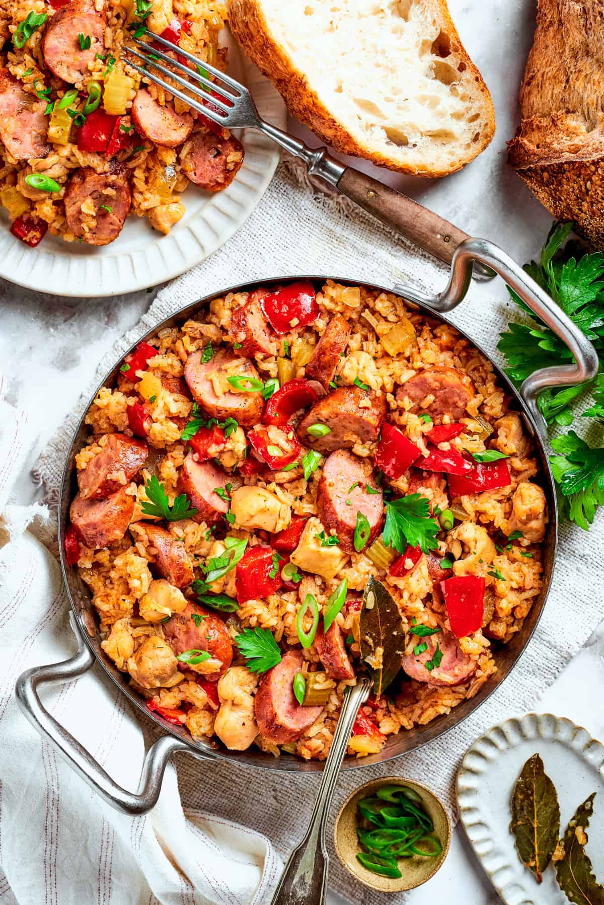 A big pan of chicken and sausage jambalaya on a table with bread.