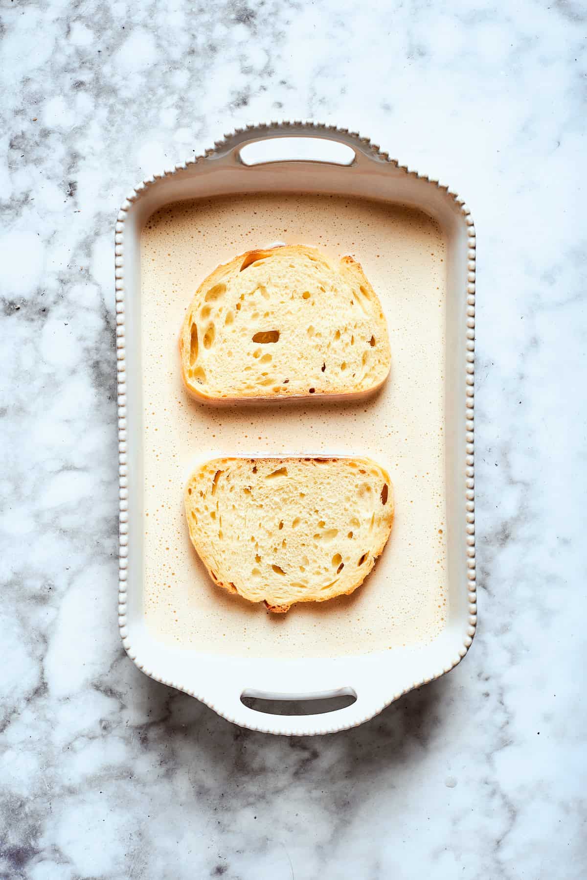 Two pieces of bread soak up the banana batter.