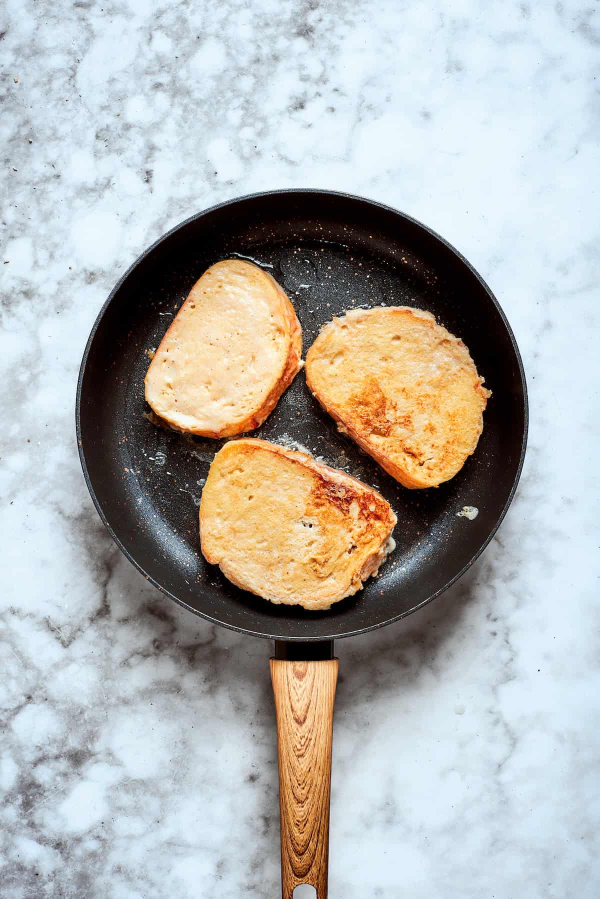 The french toasts fries in a skillet.