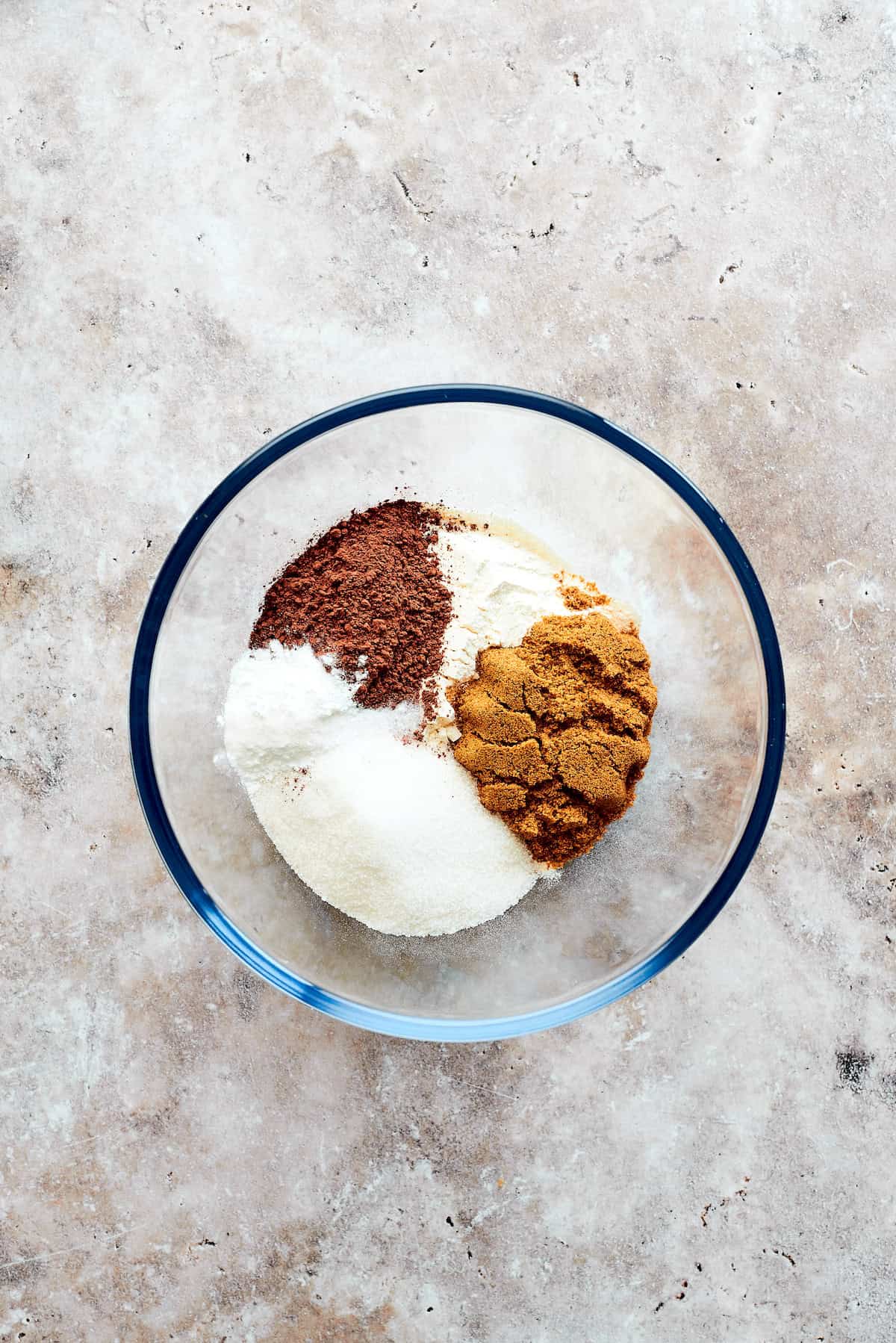 Flour, cocoa powder, and sugars are added to a bowl.