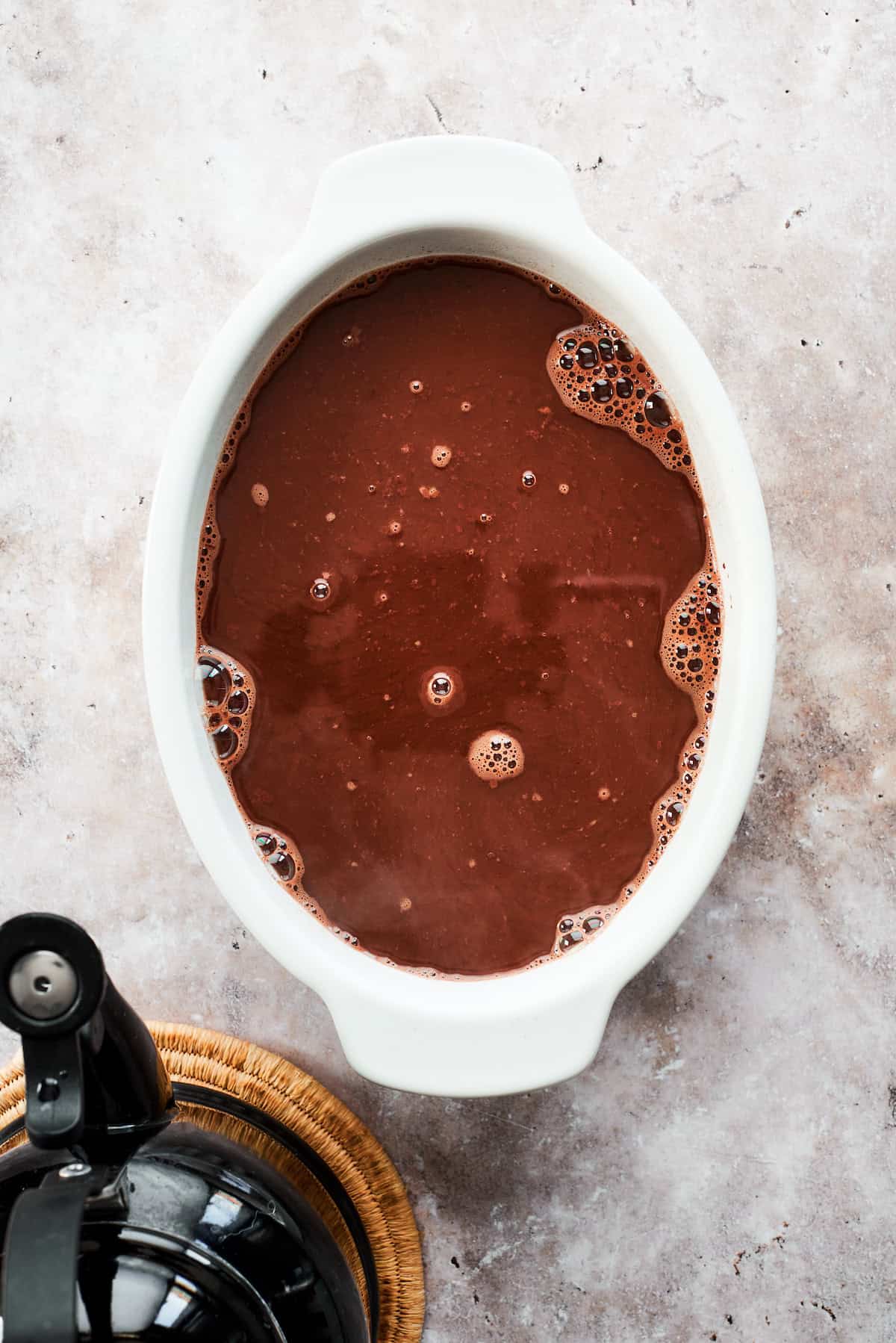 Boiling water is poured over the cake and topping in the pan.