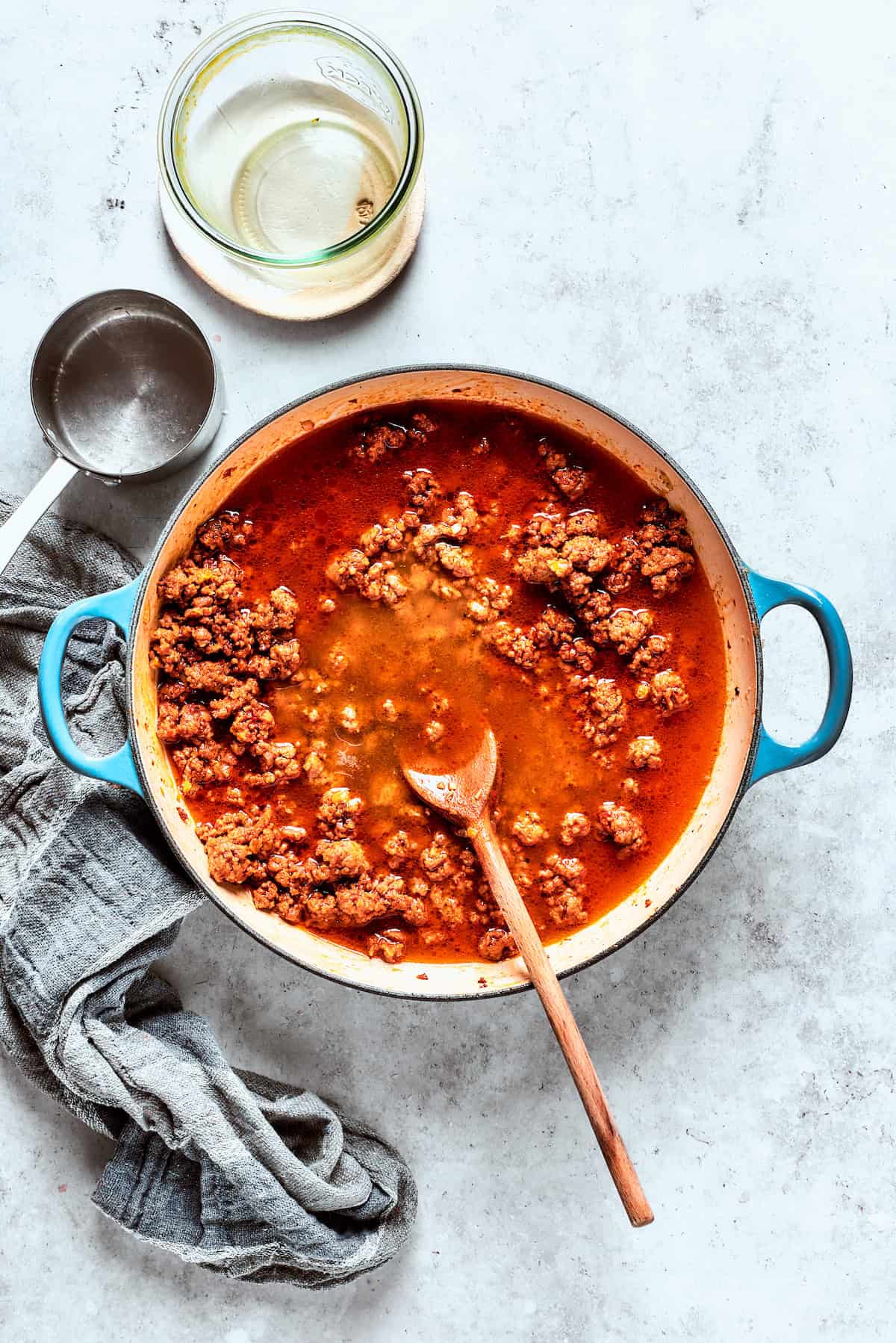 Beef cooks in broth and tomato puree in a pot.