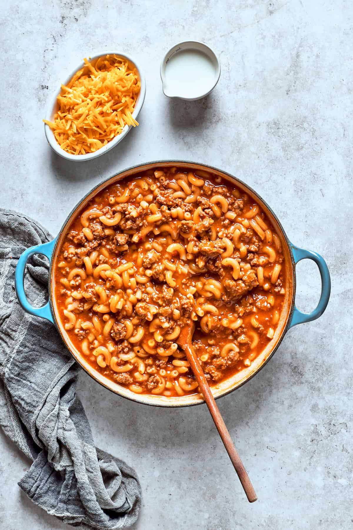 A spoon stirs together the pasta and beef.