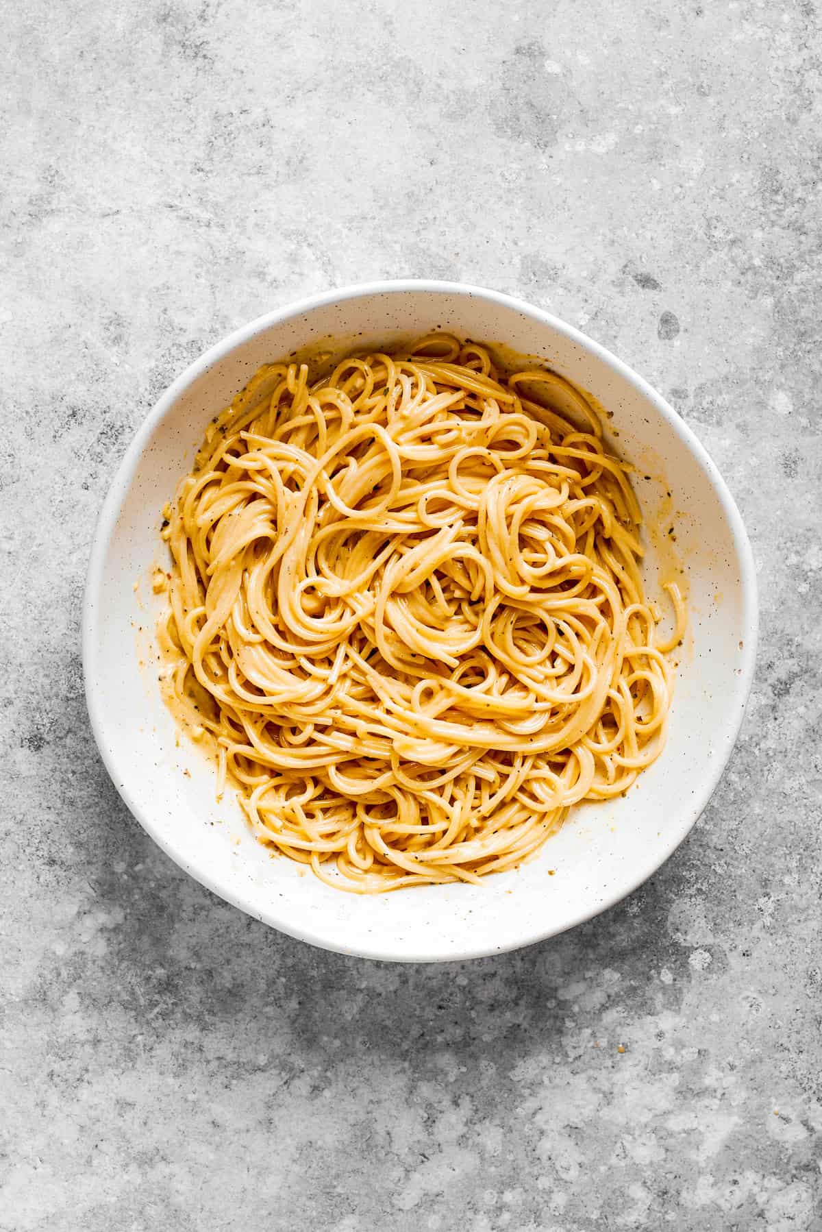 Cooked spaghetti noodles in a white bowl.
