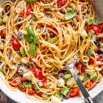 Fresh vegetables are shown in a bowl of spaghetti salad.