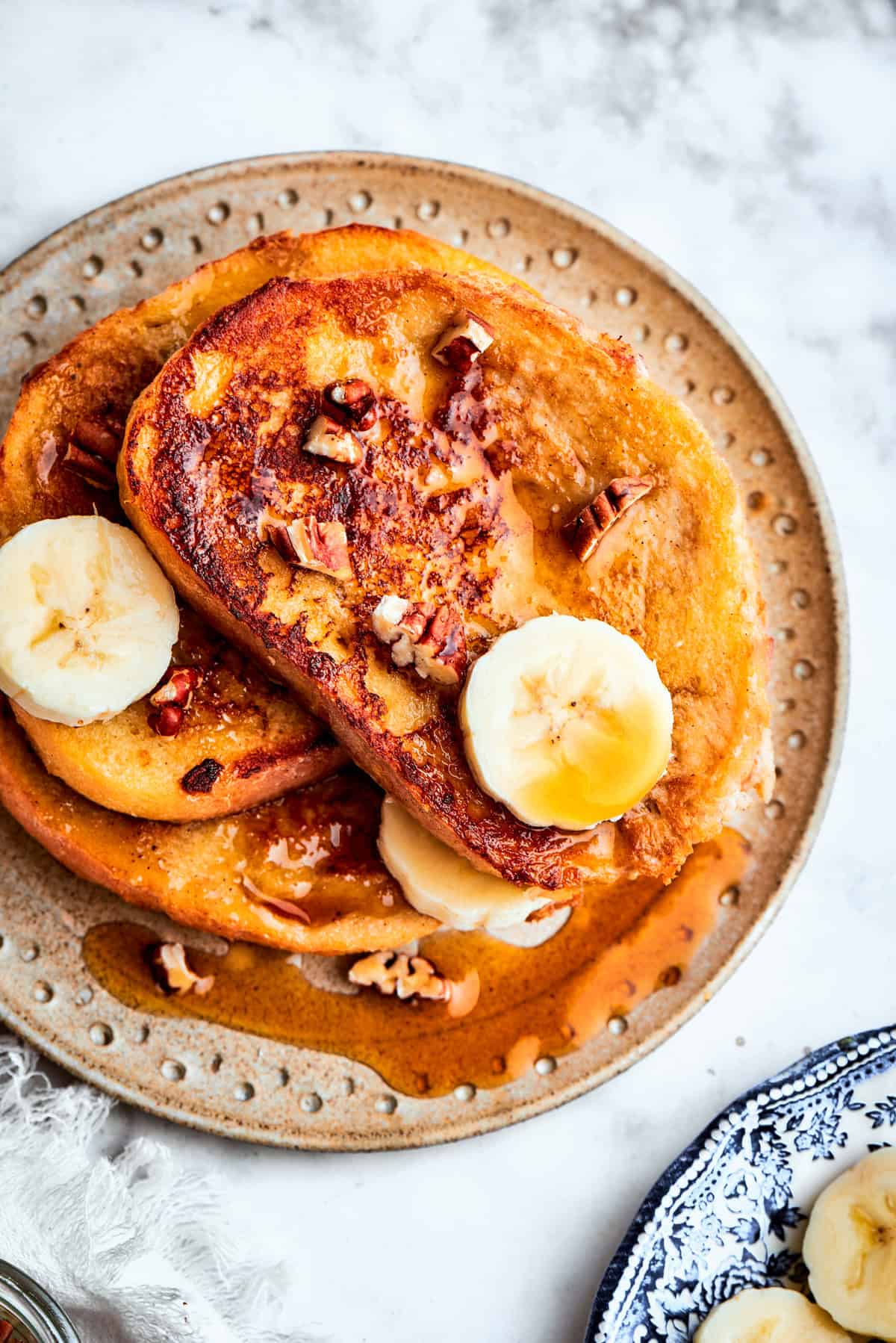 Banana toast served on a plate with a slices of banana on top.